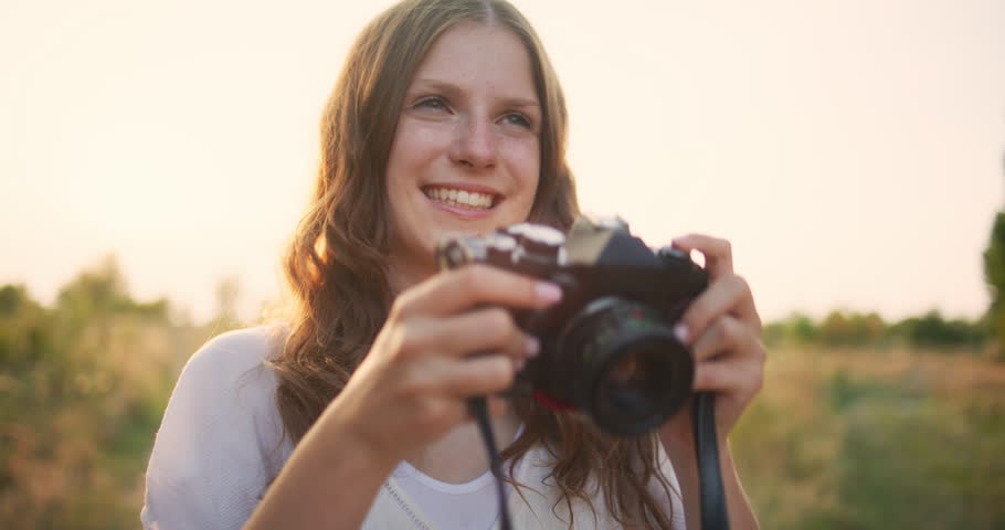 A young explorer holds her camera capturing the beauty of nature in a meadow