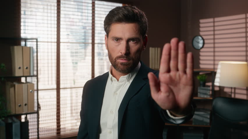 Confident serious Caucasian man male guy businessman business leader boss company CEO in office looking at camera put hand in front stop gesture enough refuse limit keep distance deny forbid protect