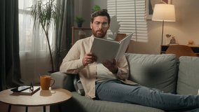 Caucasian man reading book alone at home male homeowner reader smart guy businessman in eyeglasses read literature on couch sofa paper pages textbook hobby leisure rest in apartment studying knowledge - Powered by Shutterstock - Get 15% off with code: PIKWIZARD15