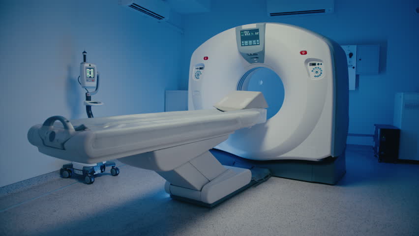 Empty MRI scanner room showing diagnostic machine with extended patient table ready for next procedure. Bright display glowing on device while scanning station remains unused and perfectly prepared.