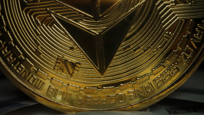 Dolly slider, close up. Golden Ethereum Coin Standing Upright on US Dollar Bills with Dramatic Lighting Against a Dark Background. Focus on Cryptocurrency as a Financial Innovation