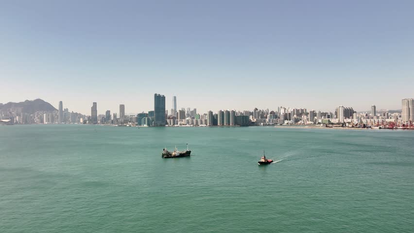 Panoramic view of Hong Kong from the sea. Modern skyscrapers line the shore of this urban commerce and finance center of China. Pan left.