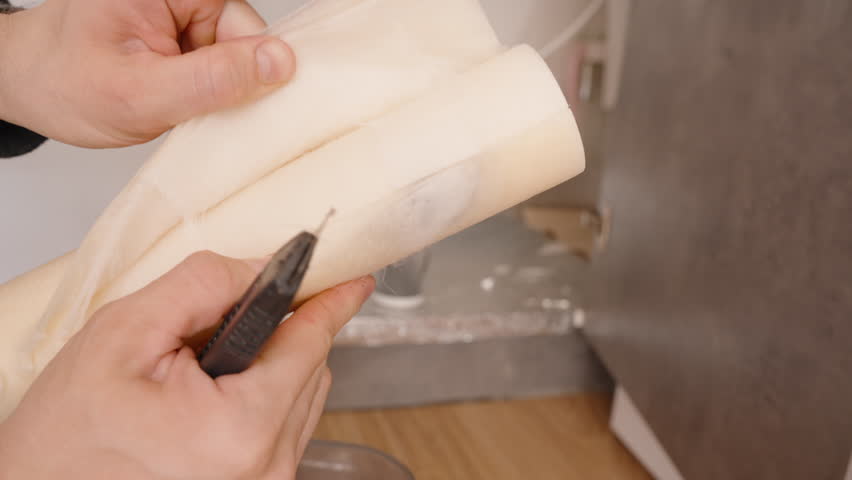 Hands Peeling Back the Layers of a Cut Open Paper Filter from a Reverse Osmosis System, Revealing the Inner Structure and Contaminants Trapped Over Time