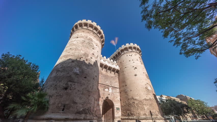 Towers of Quart timelapse hyperlapse in Valencia, Spain. Historical medieval gate, part of the ancient city walls. Popular landmark with a rich cultural heritage. Blue sky and street traffic scene.