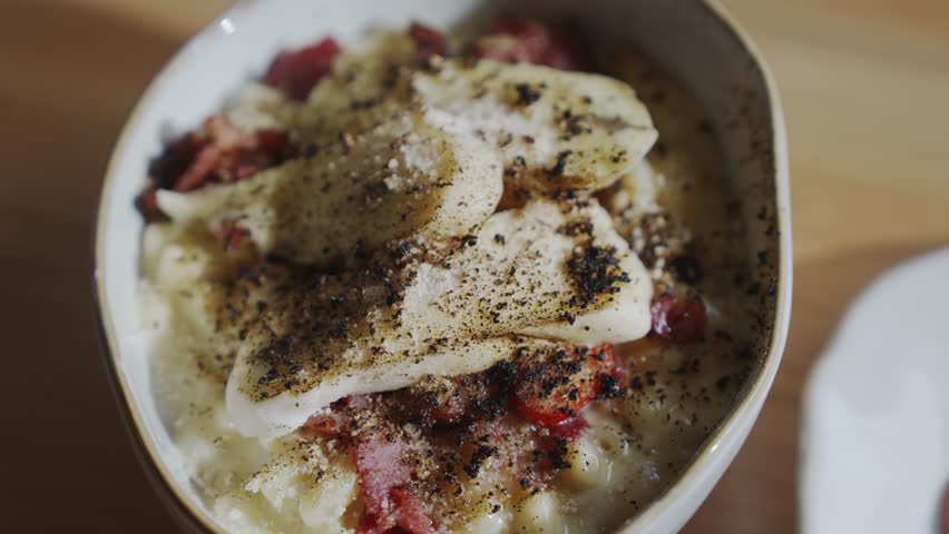 A bowl of food with a white base and a brown topping. The brown topping is made of crushed nuts and spices