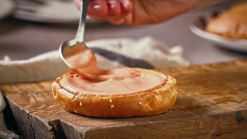 cook put sauce on bread bun on wooden cutting board, food closeup, making delicious burger
