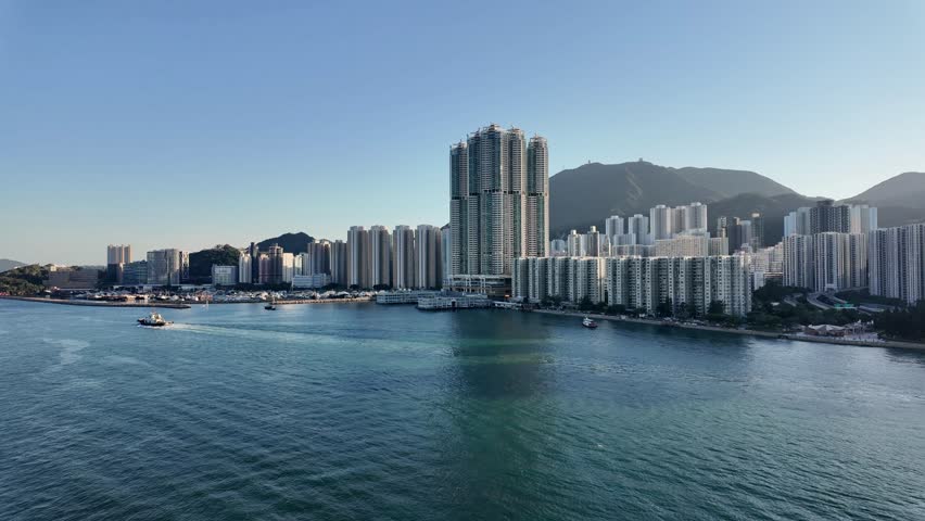 Modern skyscrapers, condos, apartments and office buildings lining the shore of urban Hong Kong. View from cruise ship of landscape and modern architecture of China.