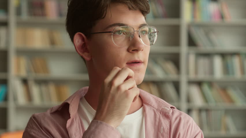 Thinking pensive thoughtful ponder serious think idea puzzled decide plan solution Caucasian teen man teenage male teenager guy boy student schoolboy pupil studying education library school university