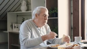 Happy senior man eating a scramble on a white plate with vegetables. Elderly male using knife and fork to cutting meal, has a breakfast. Balanced diet, cooking, culinary. Food concept. Old person - Powered by Shutterstock - Get 15% off with code: PIKWIZARD15