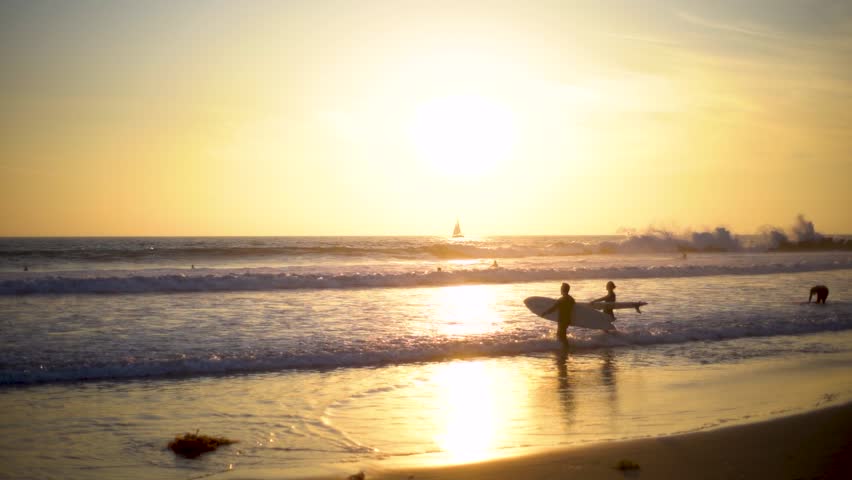 Surfers Enjoying Sunset Waves at Pacific Ocean, California