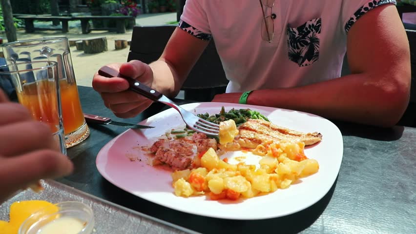 Man have a lunch with delicious cooked meat meal served with vegetables on a plate 