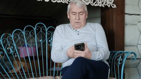 Portrait of senior man using mobile phone, holding device, texting, surfing internet. Old male looking at web camera, talking online. Elderly person chatting. Modern technologies and older generation - Powered by Shutterstock - Get 15% off with code: PIKWIZARD15