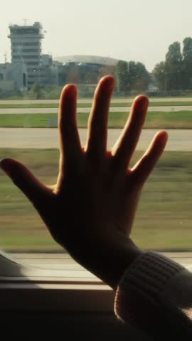 Kid s hand touching airplane window, close up. Silhouette of a child