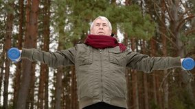 Senior man working out outdoors in winter forest. Person lifting dumbbells. Old male exercising. Healthy people lifestyle. Active sport training. Older elderly sportsman doing fitness. Workout session - Powered by Shutterstock - Get 15% off with code: PIKWIZARD15