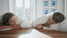 Tender lovers touching hands in sunlight closeup. Playful couple lying under blanket enjoying intimate moment at home. Affectionate man woman cozy relaxed atmosphere. Bonding relationship concept - Powered by Shutterstock - Get 15% off with code: PIKWIZARD15