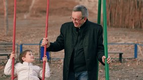Happy family. Little kid son sitting on swing smiling, father swinging child on children's swing in autumn park. Autumn, little son dad playing together on swing on playground. Family relationships - Powered by Shutterstock - Get 15% off with code: PIKWIZARD15