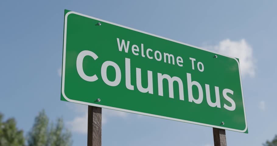 Driving By A Welcome To Columbus, Ohio Green Road Sign Against a Blue Sky and Clouds - United States Capital Series.