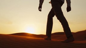Slow motion video: Silhouette of a human walking on the sands in the desert in windy weather while sunrise.  Young man in stylish clothes walks barefoot on the sand dunes in the desert at sunset. 
 - Powered by Shutterstock - Get 15% off with code: PIKWIZARD15