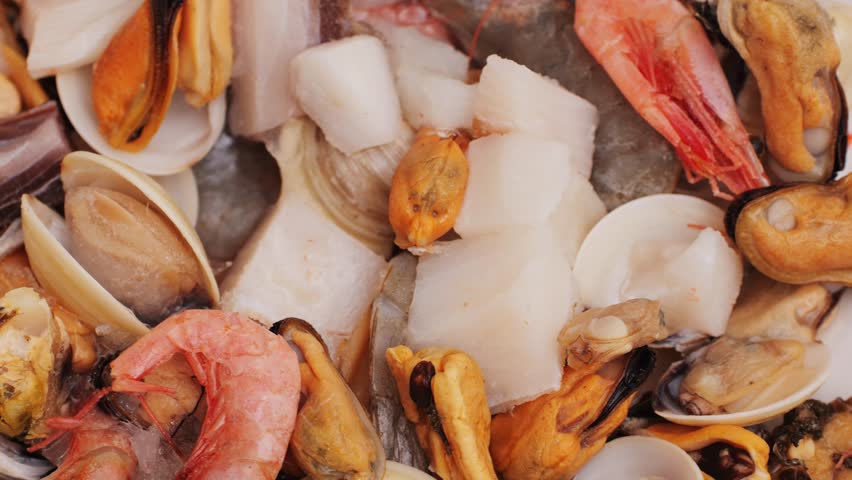 Paella mix, Roasted Mixed Seafood Contain Blue Crabs, Mussels, Big Shrimps, Calamari Squids and Grilled Barracuda Fish Garlic with Spicy Chili Sauce and Lemon on Dish, close up supermarket food.