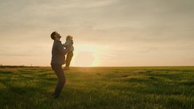 Dad throws happy daughter up in air with his hands in sun rays. Father, little child play and rejoice together. Happy family weekend in nature. Child in parent arms. Happy family concept. Green field - Powered by Shutterstock - Get 15% off with code: PIKWIZARD15