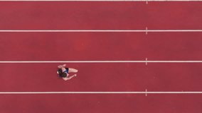 Top down view aerial drone shot of a professional female athlete sprinting on a large stadium athletics track. Dynamic slow motion cinematic footage captures her power, speed, and determination in - Powered by Shutterstock - Get 15% off with code: PIKWIZARD15