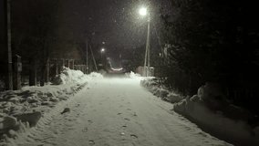 A snowy road with a street light in the background. The street light is lit up, illuminating the snow - Powered by Shutterstock - Get 15% off with code: PIKWIZARD15