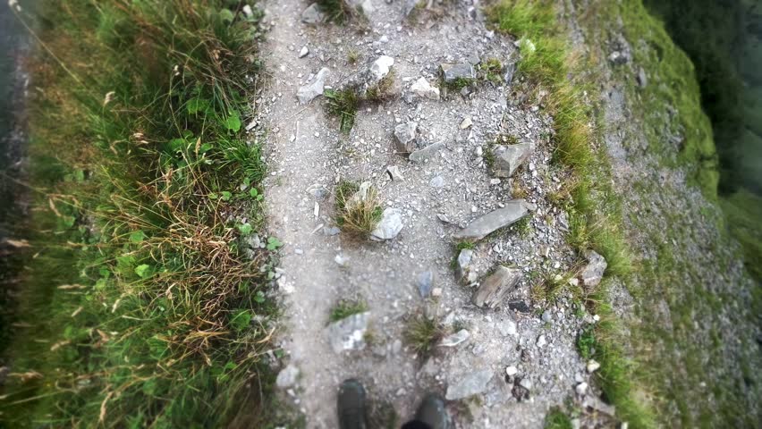 POV Hiker Walking on Narrow Mountain Cliff Trail with Gravel and Grass