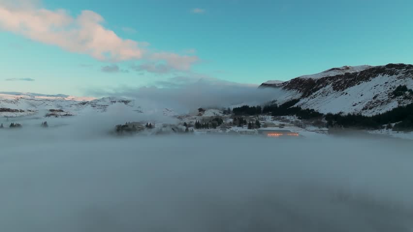 Dense Layer Of Fog Clouds Covers Snowy Landscape Of Hveragerdi In South Iceland. aerial shott