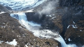 Static shot of waterfall and meltwater river in Eksingedalen. Splashing droplets, snow in background, and high voltage line show link between nature and energy - Powered by Shutterstock - Get 15% off with code: PIKWIZARD15