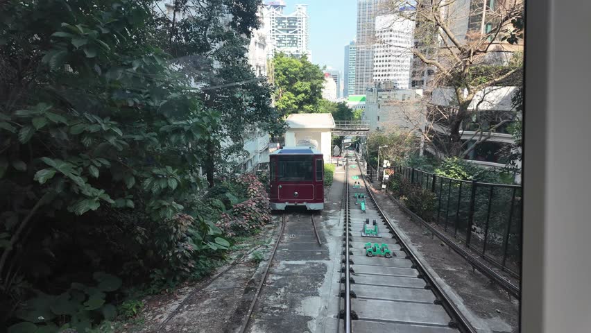 Ascending Victoria Peak of Hong Kong, China. View from inside tram. Skyscrapers and bay in background.