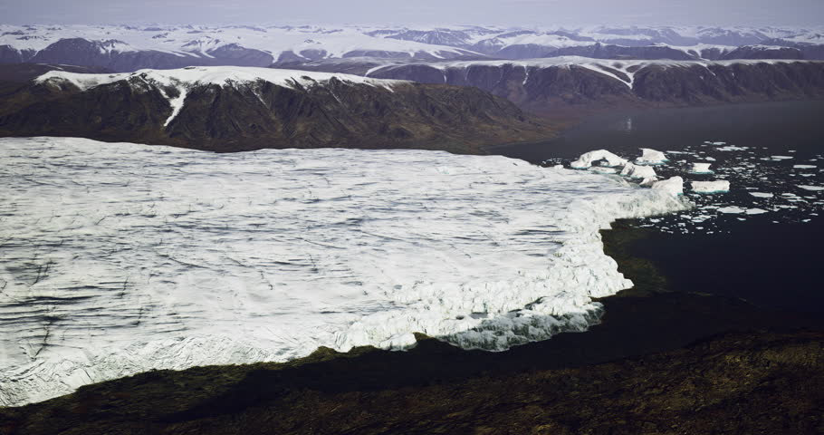 A vast expanse of ice stretches into the water, with towering mountains in the background. The scene captures the unique beauty of Greenlands remote glacial terrain.
