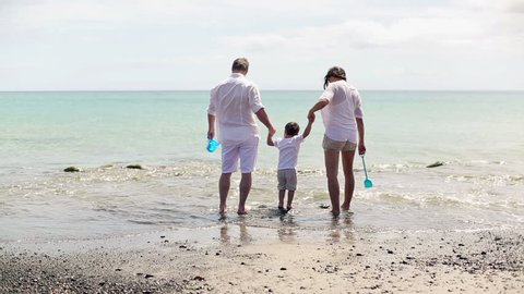 Happy family in white clothes playing on the beach
