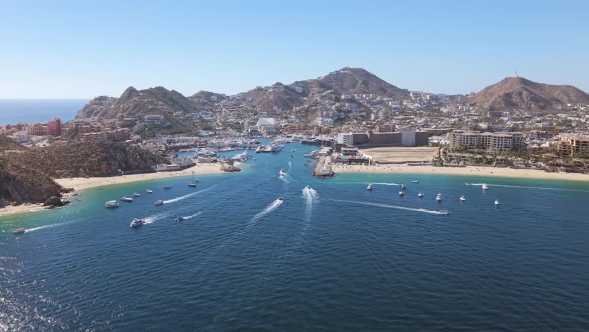 Amazing aerial towards Cabo San Lucas marina in Mexico over beach front ocean with boats all around
