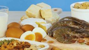 An assortment of meats, seafood, and nuts displayed on a wooden board with a blue background. - Powered by Shutterstock - Get 15% off with code: PIKWIZARD15