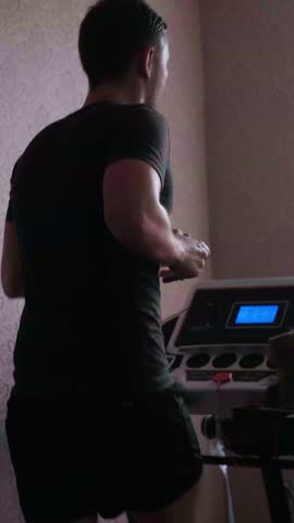 Athletic man doing cardio on a treadmill, maintaining his fitness at home with regular exercise and a healthy lifestyle. sstkWellness