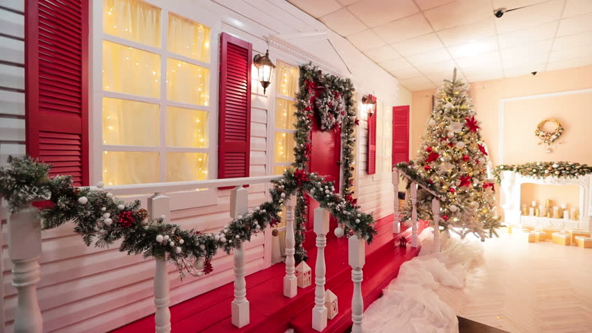Approaching a beautiful porch decorated with lovely garlands, yellow lights and festive wreaths. Christmas season photo studio decor.