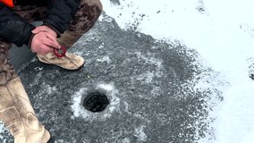 Ice fishing on frozen lake. Catching fish through an opening in the ice on a frozen body of water. Catching fish in a hole in the ice on frozen river. Winter fishing. Jigging with Small jigging rod.  - Powered by Shutterstock - Get 15% off with code: PIKWIZARD15