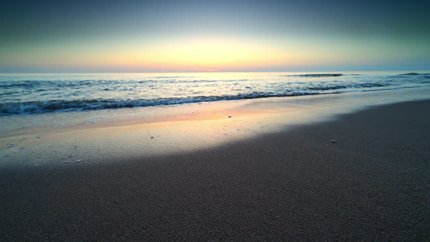 Sunset at the North Sea beach during a calm day in South Holland with gentle waves hitting the sandy beach in The Netherlands.