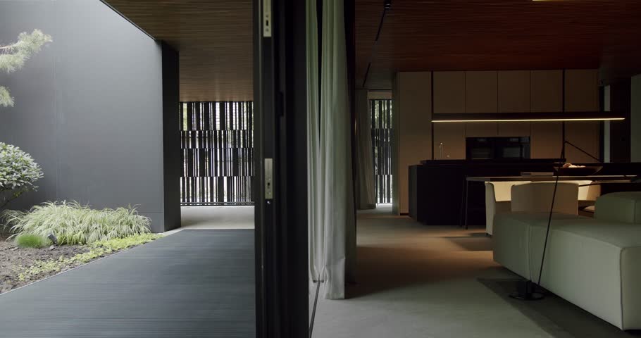 A stylish man steps into a sleek, contemporary home featuring minimalist design, a serene garden, and sophisticated interiors. Man Walking into a Modern Home with Minimalist Architecture