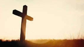 Warm sunlight illuminates a solitary wooden cross on a grassy hill. Religion and faith - Powered by Shutterstock - Get 15% off with code: PIKWIZARD15