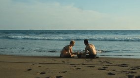 Couple sitting on beach, enjoying the sunset while building sandcastle together in El Salvador - Powered by Shutterstock - Get 15% off with code: PIKWIZARD15