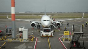 Plane with passengers, Mobile boarding, Airplane access. Using mobile staircase, passengers are boarding airplane on tarmac, with ground support staff and equipment present. - Powered by Shutterstock - Get 15% off with code: PIKWIZARD15