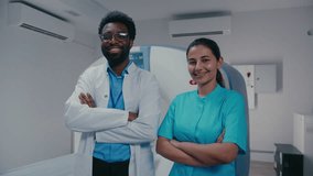 Proud clinician smiling confidently with arms folded beside composed female technician posing in radiology room. Both standing near MRI equipment showing unity after finishing imaging examination. - Powered by Shutterstock - Get 15% off with code: PIKWIZARD15