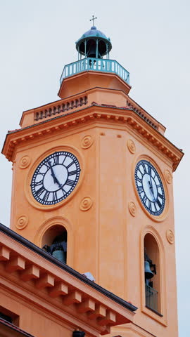 View of an orange clock tower in Nice, France with the sky on the background. Vertical