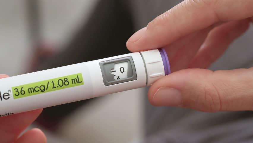 Woman's hand adjusting dosage on an injection pen for ovarian stimulation in fertility treatment
