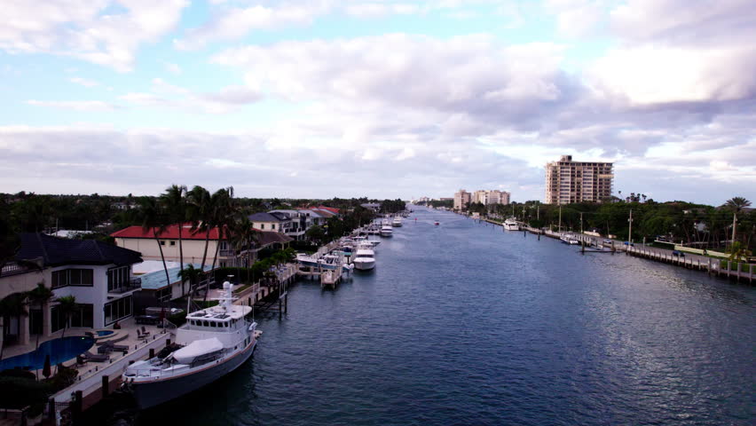 Boca Raton, Florida aerial jib up of intracoastal waterway. Boats, yachts, and luxury homes line the waterway up to the horizon. The Atlantic Ocean is visible to the right.
