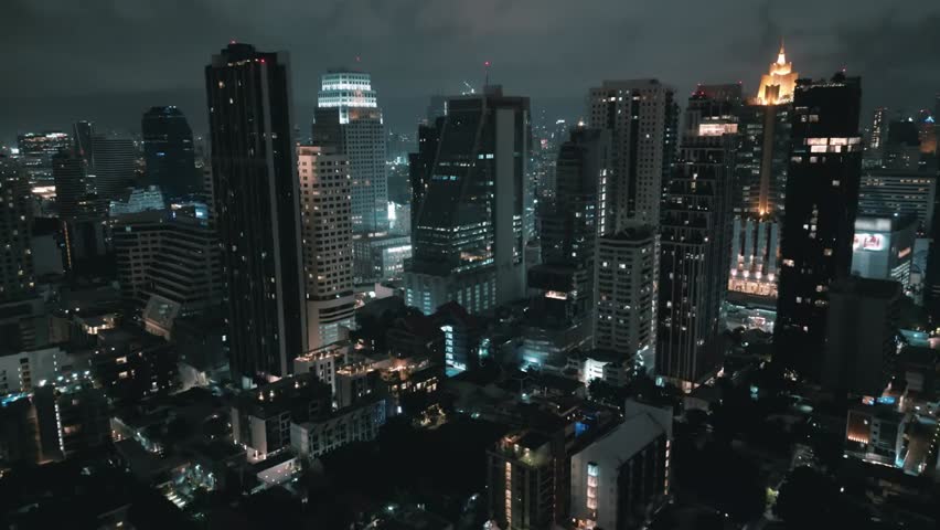 Epic drone footage capturing a cinematic nighttime metropolis with a towering aerial view. The breathtaking beauty of Bangkok’s iconic skyline, illuminated streets, and vibrant city life.
