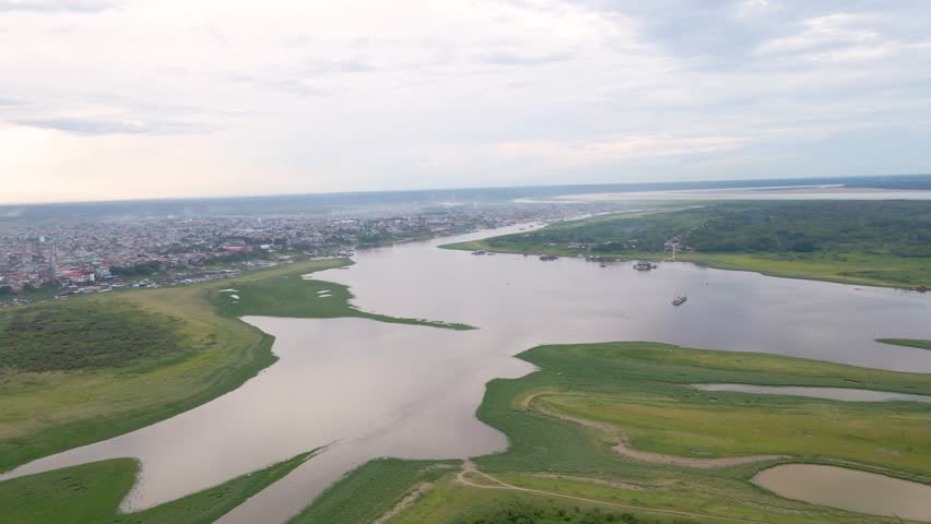 River flowing by Iquitos city, lush green banks under cloudy sky, peaceful atmosphere