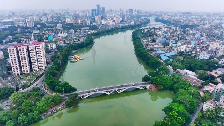 A central urban area Hatirjheel in Dhaka, Bangladesh, highlighting modern bridges, lush greenery, and a serene lake. Surrounded by high-rise buildings and roads