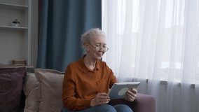 Senior woman laughing and waving as she enjoys a lively video conversation with someone on her tablet - Powered by Shutterstock - Get 15% off with code: PIKWIZARD15
